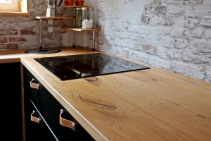 Plan de travail en bois massif dans une cuisine au style industriel et une découpe pour une plaque de cuisson